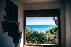 Damaged wall with ocean out of the window.